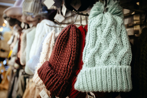 Gestrickte warme Mützen hängen auf Kleiderbügel im Geschäft - Foto, Bild