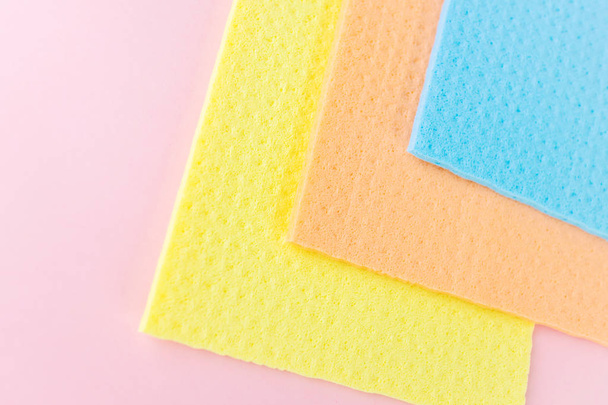 Trapos nuevos para la limpieza en húmedo. Trapos azules, amarillos y anaranjados sobre fondo rosa. El concepto de limpieza, minimalismo. Lugar para el texto
. - Foto, imagen