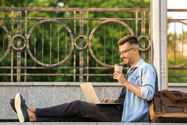 Retrato de hombre de negocios guapo con portátil y taza de café al aire libre
 - Foto, Imagen