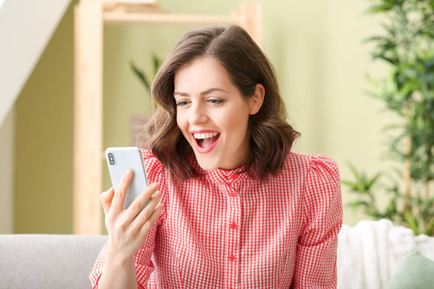 Mujer joven feliz con teléfono móvil en casa
 - Foto, imagen