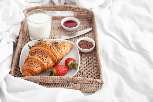 Bandeja con sabroso croissant, fresa y leche en la cama
 - Foto, imagen