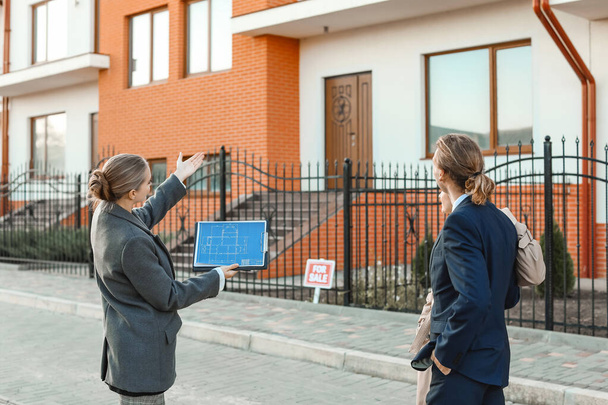 Agent nieruchomości pokazuje młodej parze nowy dom na świeżym powietrzu - Zdjęcie, obraz
