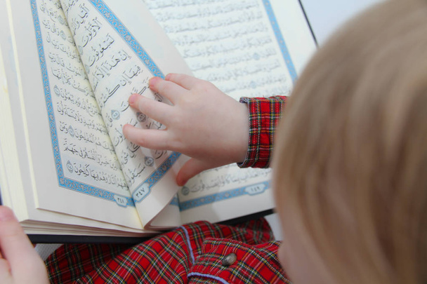 Kleine moslim Europese jongen met islamitisch heilig boek Koran of Kuran - Foto, afbeelding