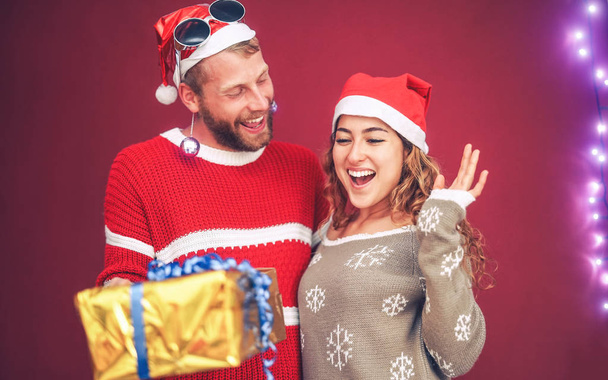 Happy couple celebrating Christmas time sharing presents - Young people having fun during x-mas holidays - Xmas vacation and traditional culture lifestyle concept - Φωτογραφία, εικόνα