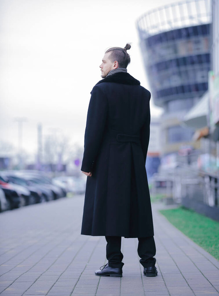 young business man in a winter coat standing on the street - Фото, изображение