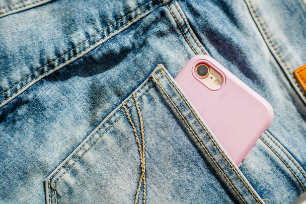 Modern smartphone in the pocket of jeans, close-up, Cell phone in the pocket of jeans in blue jeans, denim background texture - Foto, immagini