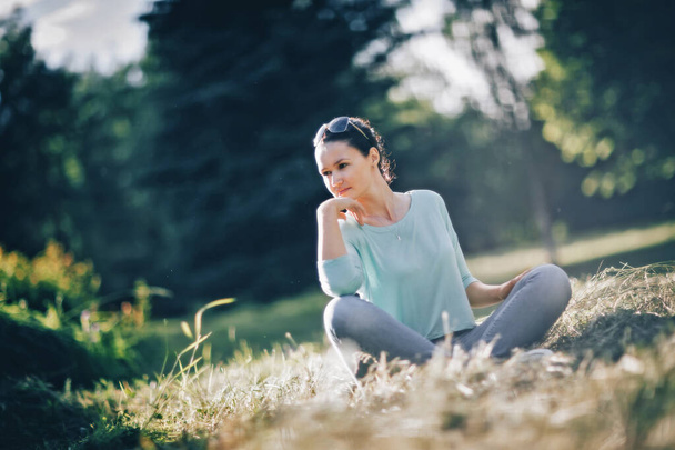 pensive young woman sitting in Lotus position in city Park - Fotó, kép
