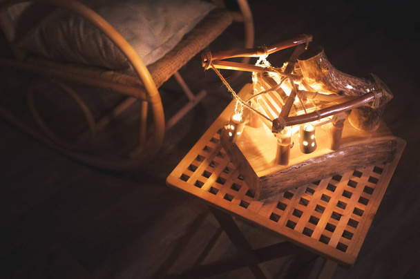 Κοντινό πλάνο ξύλινο αμπαζούρ με οπίσθιο φωτισμό και κουνιστή καρέκλα σε ένα κακοφτιαγμένο υπνοδωμάτιο τη νύχτα. Αρχική έννοια άνεση - Φωτογραφία, εικόνα
