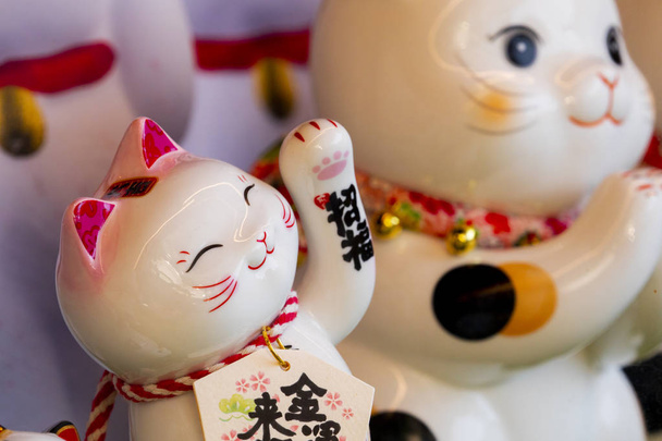Un grupo de gatos afortunados japoneses de cerámica en la vitrina (subtítulo: Lucky Cat, Jin Yun Laifu
) - Foto, imagen