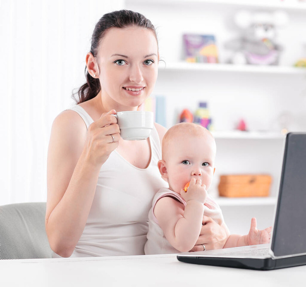 young mom with little baby sitting at the Desk.the concept of freelancing - Fotoğraf, Görsel