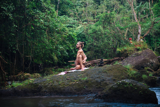 Yoga practice and meditation in nature. Man practicing near river - Photo, image
