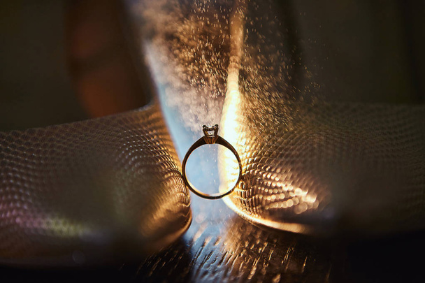 Diamantový snubní prsten mezi botami nevěsty se šplouchnutím parfému v pozadí - Fotografie, Obrázek