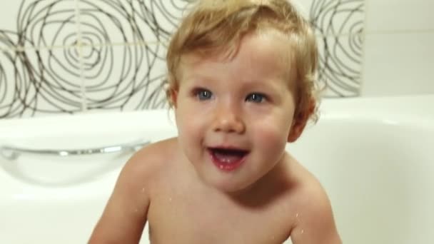 Счастливый голубоглазый малыш 9-12 месяцев купается в ванной и играет с игрушками, моет и купает детей, ухаживает за маленькими детьми
 - Кадры, видео