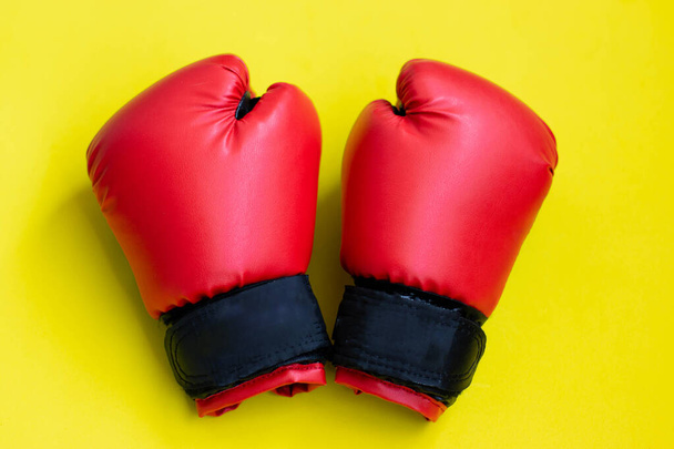 Red boxing gloves on a yellow background. - Foto, afbeelding