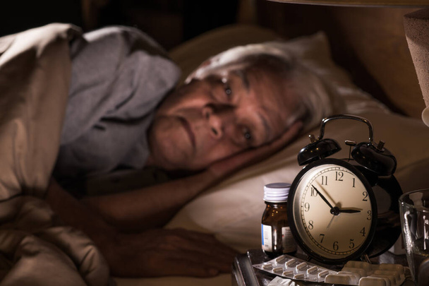 Депрессивный мужчина, лежащий в постели, не может уснуть от бессонницы.
 - Фото, изображение