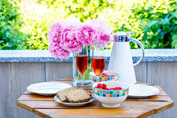 Ontbijttafel met brood, drust groenten en bessen, koffie en champagne geserveerd op balkon of hotel op Zomerochtend - Foto, afbeelding