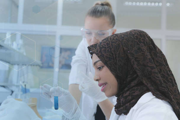 Две мультиэтнические молодые женщины-учёные проводят эксперименты в лаборатории - Фото, изображение