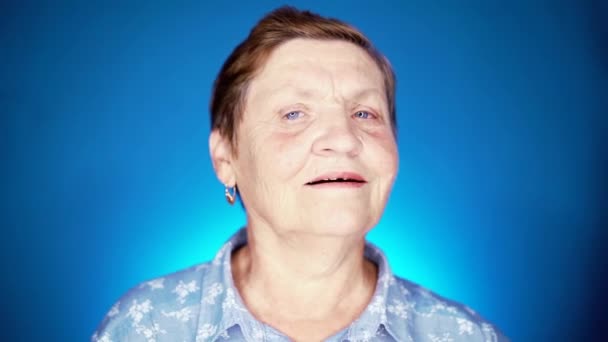 Woman pensioner on blue background with dollars. Grandmother smiling, she happy to get benefits with paper currency. - Záběry, video
