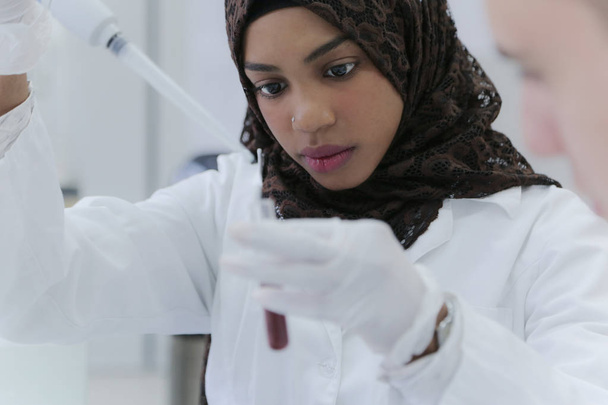 Νεαρή γυναίκα Αφρικανή επιστήμονας που κάνει πειράματα στο εργαστήριο - Φωτογραφία, εικόνα