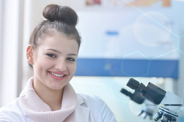 Νεαρή γυναίκα επιστήμονας κοιτάζοντας κάμερα και χαμογελώντας κατά τη διάρκεια exp - Φωτογραφία, εικόνα