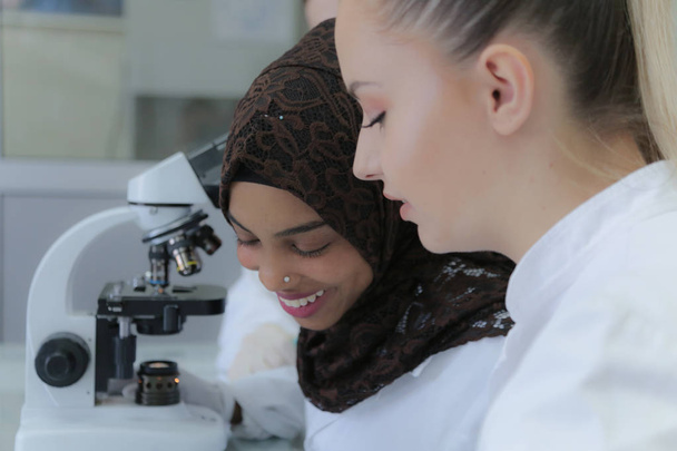 Δύο πολυεθνικές νέες γυναίκες επιστήμονες που κάνουν πειράματα στο εργαστήριο - Φωτογραφία, εικόνα