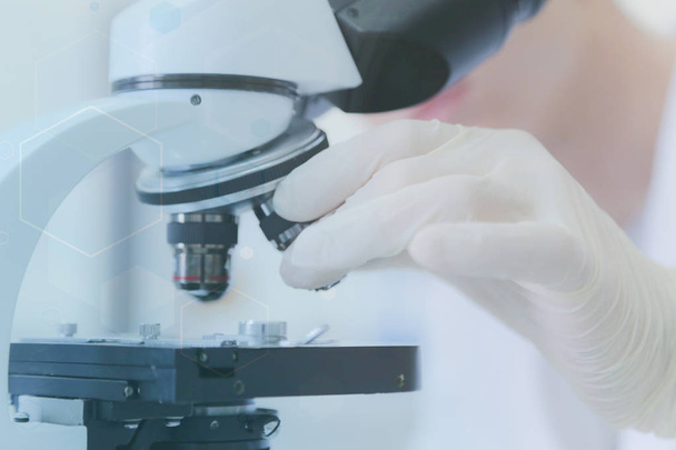 Giovane scienziato maschio che guarda attraverso un microscopio in un laboratorio - Foto, immagini