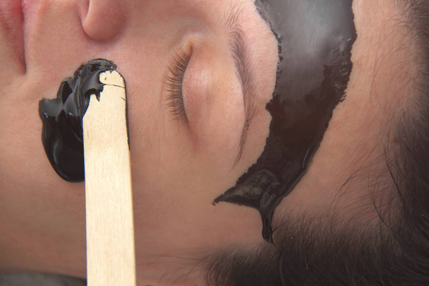 Junge schöne Frau unter Anwendung schwarzer Holzkohle Gesichtsmaske. Haut  - Foto, Bild