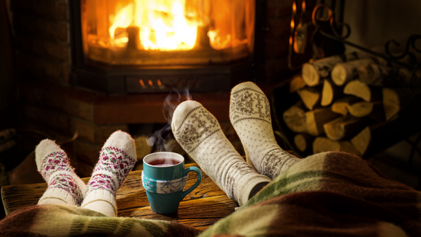 Warme sfeer bij de open haard. Vrouwelijke en kindervoeten in wollen sokken, stoom stijgt op uit een warme drank. - Video