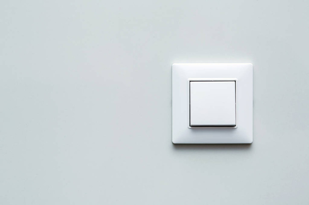 um interruptor de luz, um botão mecânico de plástico de cor branca instalado em uma parede de luz com espaço de cópia para texto
. - Foto, Imagem