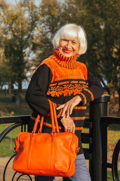 Dreamy old woman expressing positive emotions. Portrait of a happy old beautiful woman in a park in autumn. - Zdjęcie, obraz