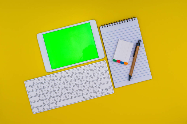 文房具、黄色の背景に緑の画面のタブレット - 写真・画像