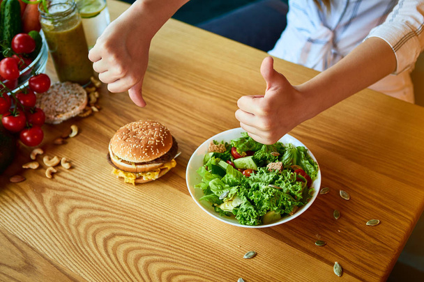 De vrouw weigert ongezonde hamburger te eten. Goedkope junk food vs gezonde voeding - Foto, afbeelding