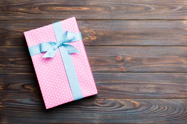 бумажная подарочная коробка с цветной лентой на темном фоне дерева. Концепция рождественских праздников - Фото, изображение