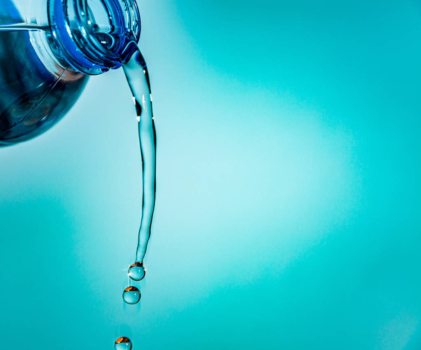 pouring water from a bottle on a blue background - Foto, Imagen