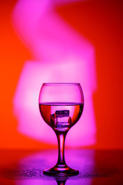 a glass with a drink on a beautiful red background illuminated w - Photo, image