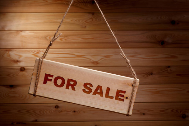 Wooden signboard with the words FOR SALE on a rough rope on a beautiful wooden background - Photo, image