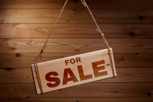 Wooden signboard with the words FOR SALE on a rough rope on a beautiful wooden background - Foto, Imagen