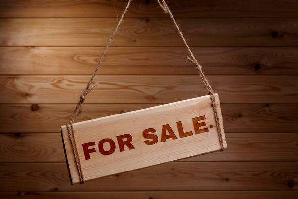 Wooden signboard with the words FOR SALE on a rough rope on a beautiful wooden background - Foto, Bild