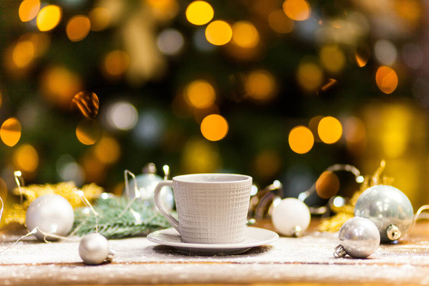 Weißer Kaffeebecher mit goldglänzendem Weihnachtsschmuck. - Foto, Bild