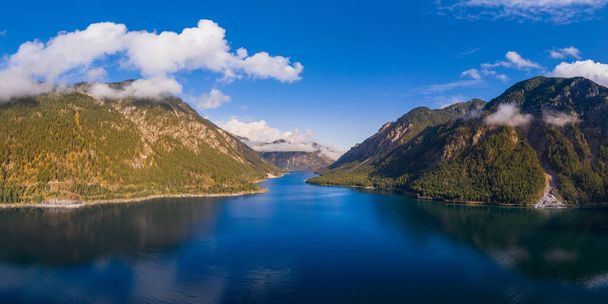 panorama of deep blue Plansee with cloudy sky and mount Zwieselberg Geierkoepfe and Spiessberg - Photo, Image