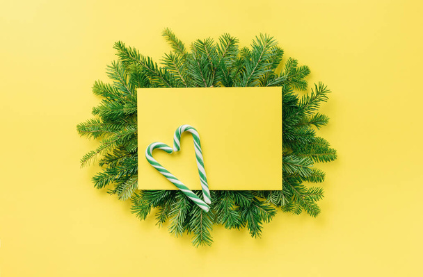 Christmas composition. Christmas decorations, gift on a fir branch on a yellow background. Flat lay, top view, copy space - Фото, зображення