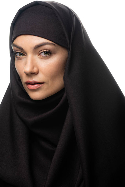 όμορφη νεαρή μουσουλμάνα γυναίκα σε μαντίλα κοιτάζοντας κάμερα απομονωμένη σε λευκό - Φωτογραφία, εικόνα