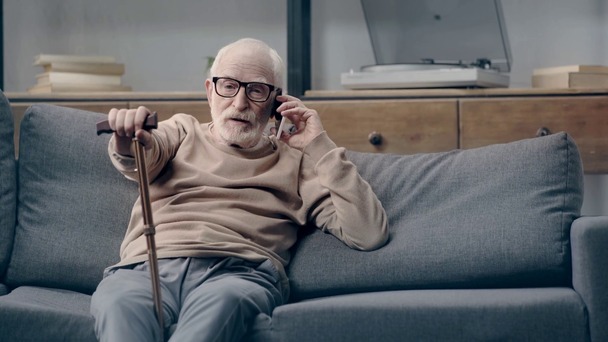 Senior man aan het praten op smartphone op de bank - Video