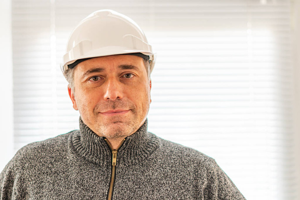 Portret uśmiechniętego inżyniera budowlanego lub pracownika fabryki noszącego biały kask i patrzącego w kamerę - Zdjęcie, obraz