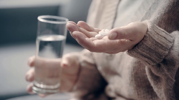 Senior woman with dementia holding pills and glass of water - Footage, Video