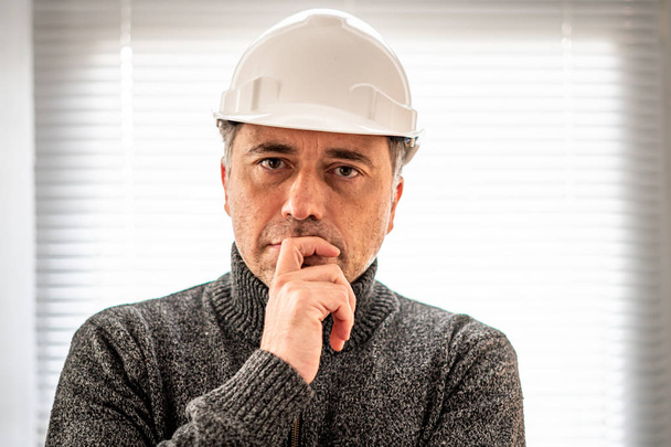 Портрет серйозного і суворого інженера-будівельника або заводського робітника в білому шоломі і дивлячись на камеру
 - Фото, зображення