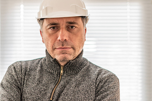 Portret poważnego i surowego inżyniera budowlanego lub pracownika fabryki noszącego biały kask i patrzącego w kamerę - Zdjęcie, obraz