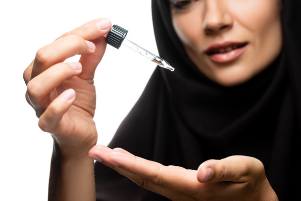foco seletivo da jovem muçulmana no hijab segurando conta-gotas com soro isolado em branco
 - Foto, Imagem