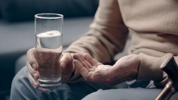 Demenzkranker Senior hält Tabletten und Glas Wasser in der Hand - Filmmaterial, Video