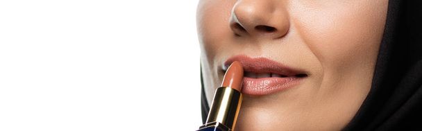 cropped view of young Muslim woman in hijab applying beige lipstick isolated on white, panoramic shot - Zdjęcie, obraz